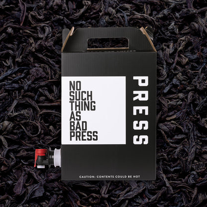 Black box with 'No Such Thing as Bad Press' text on a bed of dark tea leaves.